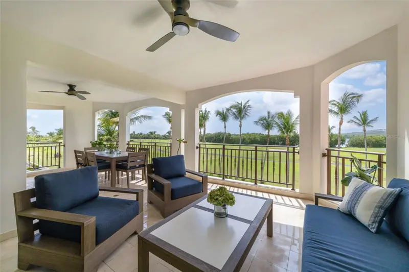 Covered terrace with outdoor seating overlooking palms and golf greens