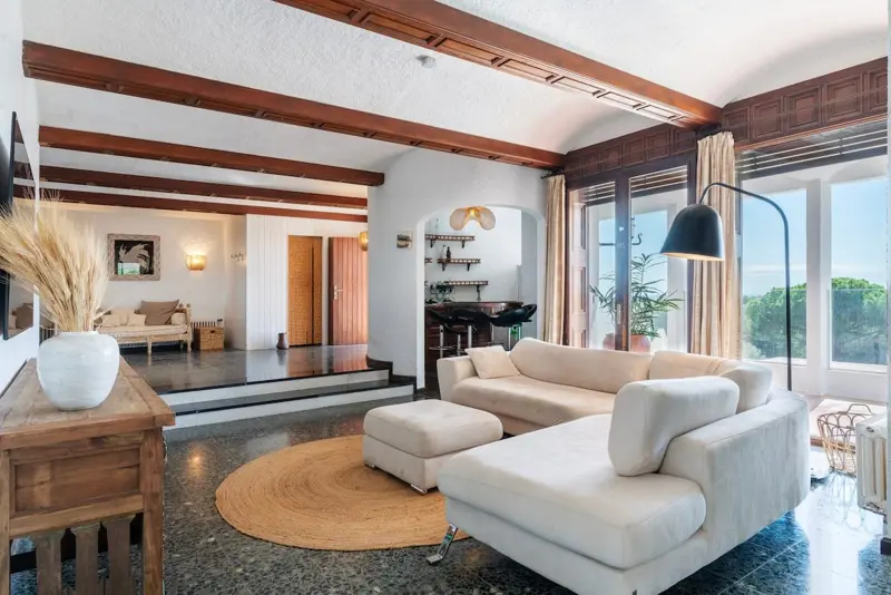 Villa living room with wood-beamed ceiling and cream sofas